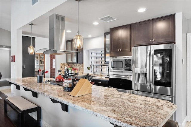 kitchen featuring a breakfast bar, pendant lighting, and island exhaust hood