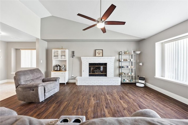 living room featuring a brick fireplace, dark wood-type flooring, lofted ceiling, and ceiling fan