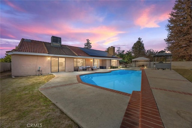 pool at dusk featuring central AC unit, a gazebo, a patio, a yard, and an outdoor hangout area