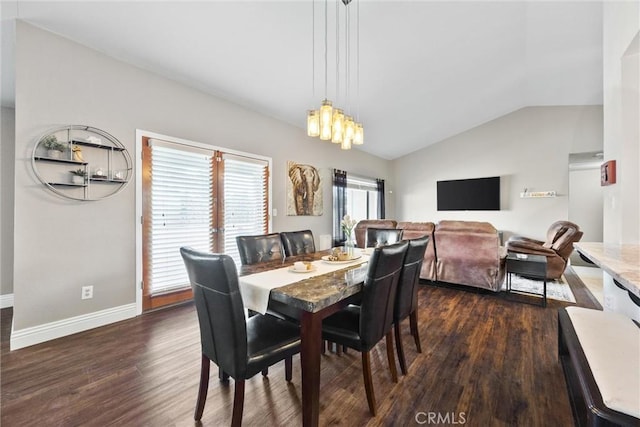 dining space with dark wood-type flooring, lofted ceiling, and an inviting chandelier