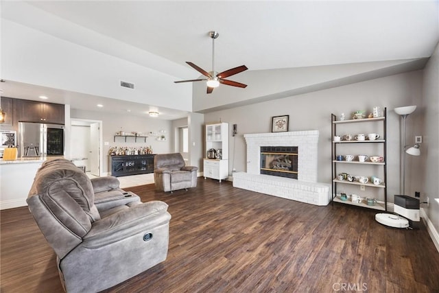 living room featuring vaulted ceiling, ceiling fan, a fireplace, and dark hardwood / wood-style floors