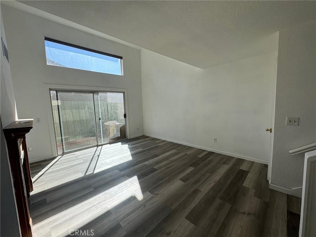 unfurnished living room with dark wood-type flooring and a textured ceiling