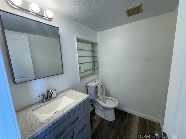 bathroom with toilet, vanity, a textured ceiling, and hardwood / wood-style flooring