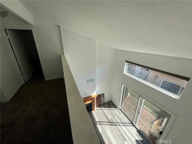 hallway with a textured ceiling and vaulted ceiling