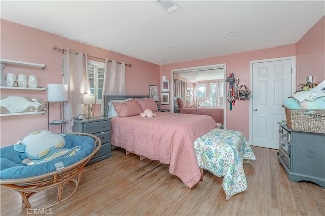 bedroom featuring light wood-style flooring, visible vents, and a closet