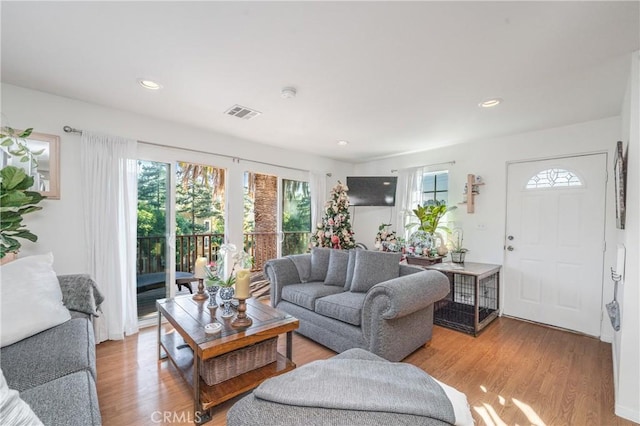 living area with light wood-type flooring, visible vents, and recessed lighting