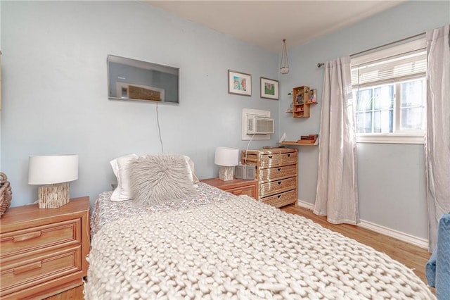 bedroom featuring baseboards, wood finished floors, and a wall mounted AC