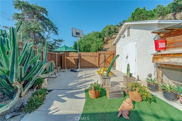 view of patio / terrace with an outbuilding, fence, and a storage shed