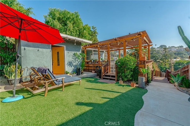 back of house with a deck, fence, a lawn, stucco siding, and a pergola