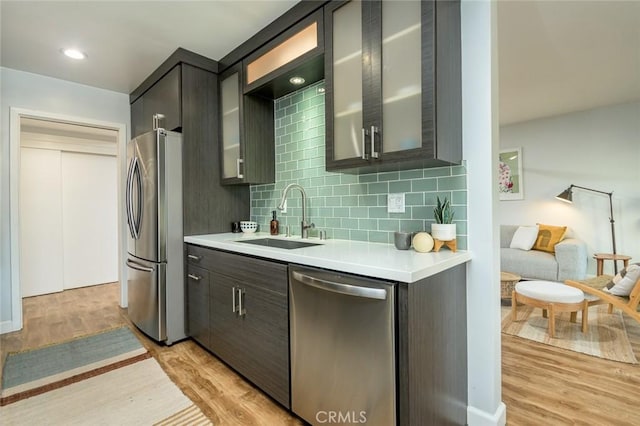 kitchen featuring appliances with stainless steel finishes, light hardwood / wood-style floors, backsplash, and sink