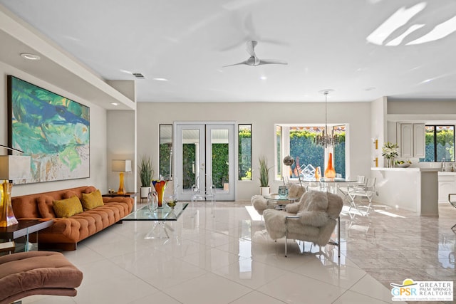 living room with plenty of natural light, ceiling fan with notable chandelier, light tile patterned floors, and french doors