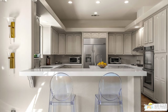 kitchen featuring stainless steel appliances, a breakfast bar, sink, and kitchen peninsula