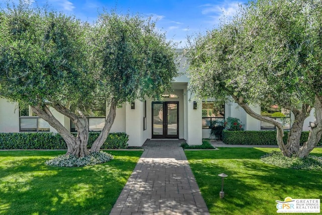 entrance to property featuring a yard and french doors