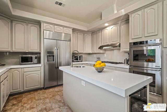 kitchen featuring sink, backsplash, a kitchen island, and appliances with stainless steel finishes