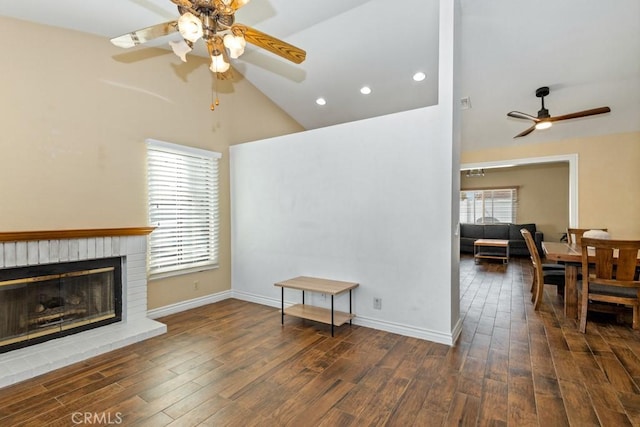 living room with high vaulted ceiling, ceiling fan, a brick fireplace, and dark hardwood / wood-style flooring