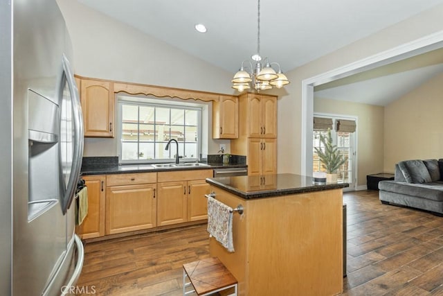 kitchen with a notable chandelier, a kitchen island, sink, hanging light fixtures, and appliances with stainless steel finishes