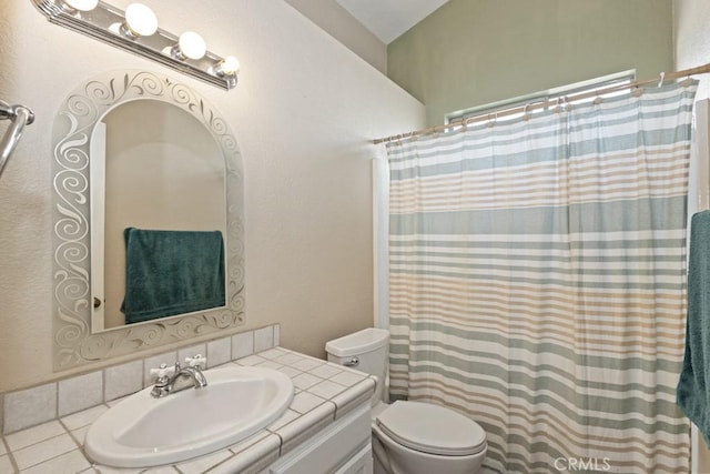 bathroom featuring toilet, tile patterned flooring, vaulted ceiling, and vanity