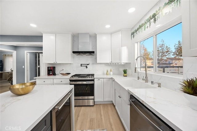 kitchen featuring stainless steel appliances, wall chimney exhaust hood, and white cabinets