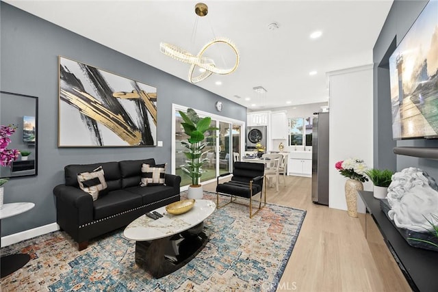 living room with stacked washer / drying machine, a chandelier, and light hardwood / wood-style floors