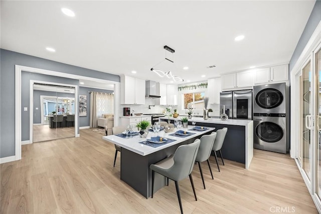 kitchen featuring stacked washer and clothes dryer, a kitchen island, stainless steel appliances, and white cabinetry