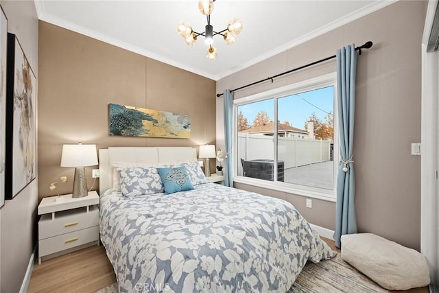 bedroom with light wood-type flooring, an inviting chandelier, and ornamental molding