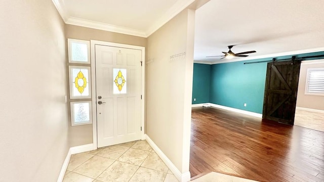 tiled foyer entrance featuring ceiling fan, ornamental molding, and a barn door