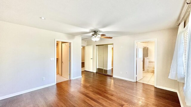 unfurnished bedroom with ceiling fan, hardwood / wood-style flooring, and ensuite bath