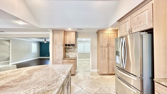 kitchen featuring light tile patterned floors, stainless steel refrigerator with ice dispenser, ceiling fan, light brown cabinets, and light stone counters