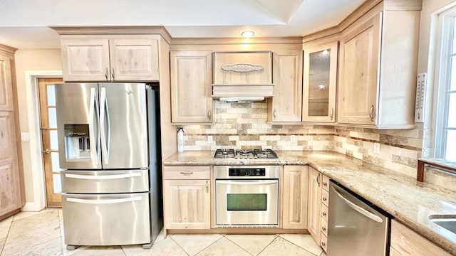 kitchen featuring light stone countertops, light tile patterned floors, light brown cabinetry, and appliances with stainless steel finishes