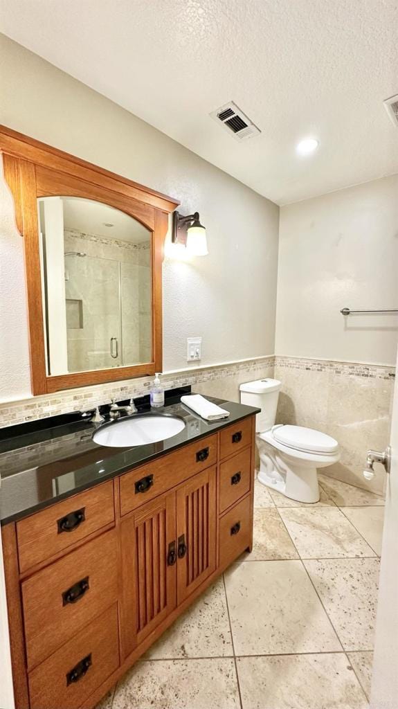 bathroom with a textured ceiling, toilet, tile walls, and vanity