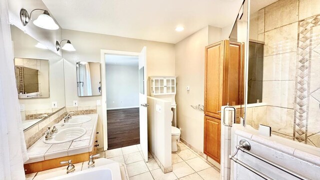 bathroom featuring toilet, vanity, tile patterned flooring, and a bath