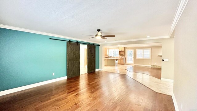 interior space with hardwood / wood-style flooring, ceiling fan, ornamental molding, and a barn door