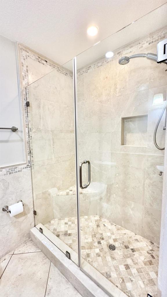 bathroom featuring a textured ceiling, tile walls, tile patterned floors, and a shower with door