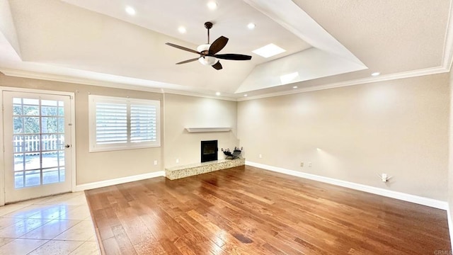 unfurnished living room featuring ceiling fan, ornamental molding, a raised ceiling, and light wood-type flooring