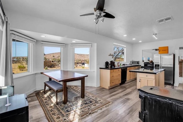 kitchen with a center island, black appliances, light brown cabinetry, light hardwood / wood-style floors, and ceiling fan