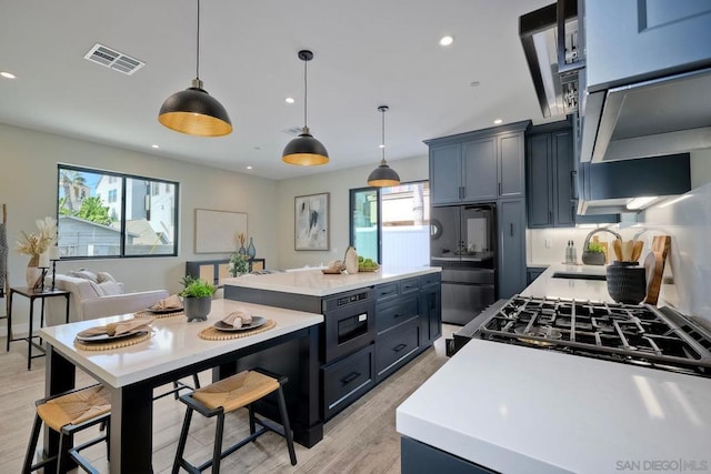 kitchen with stainless steel fridge, blue cabinetry, built in microwave, pendant lighting, and sink