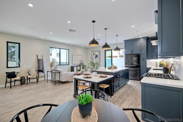 kitchen with built in fridge, light hardwood / wood-style floors, blue cabinetry, and hanging light fixtures