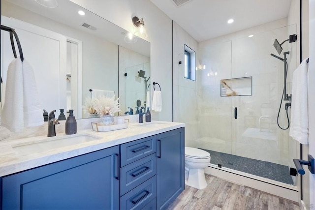 bathroom with toilet, hardwood / wood-style floors, a shower with door, and vanity