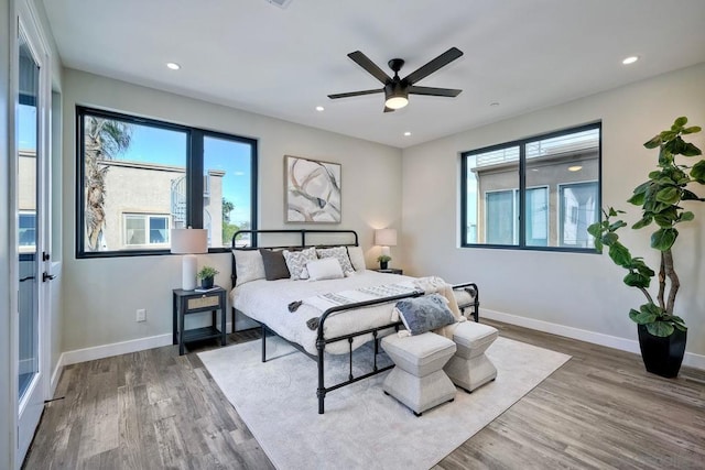 bedroom featuring ceiling fan, wood-type flooring, and multiple windows