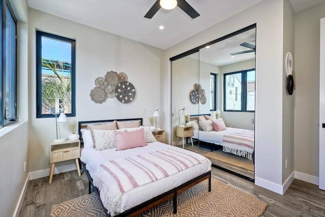 bedroom featuring ceiling fan, a closet, multiple windows, and hardwood / wood-style floors