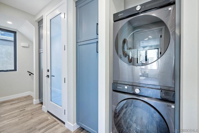 laundry room featuring stacked washer / drying machine and light hardwood / wood-style flooring