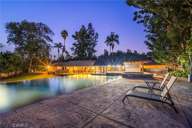 pool at dusk featuring a patio