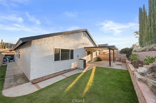 rear view of house with a lawn, central air condition unit, and a patio area