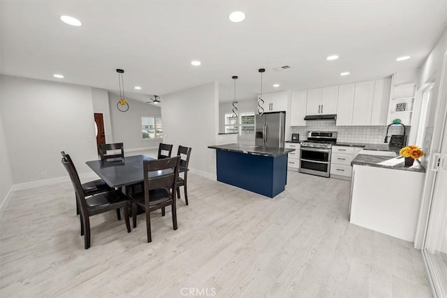 kitchen featuring decorative light fixtures, a kitchen island, sink, appliances with stainless steel finishes, and white cabinets