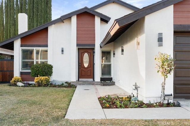 doorway to property with a garage and a lawn