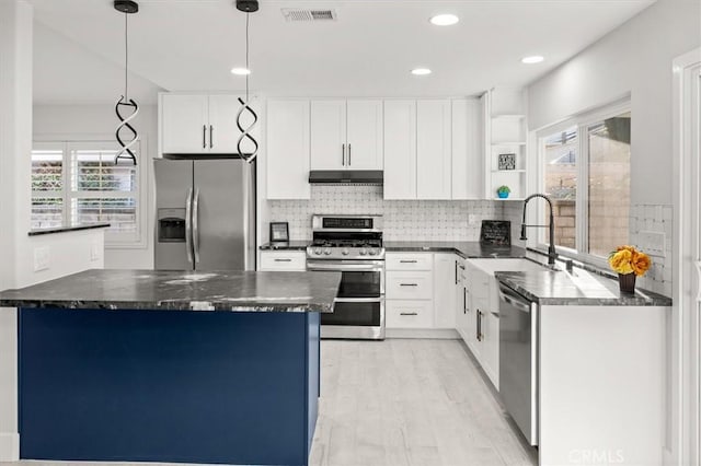 kitchen featuring dark stone counters, pendant lighting, stainless steel appliances, and white cabinetry