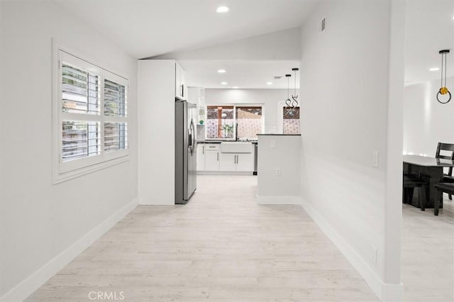 corridor with vaulted ceiling, light hardwood / wood-style floors, and sink