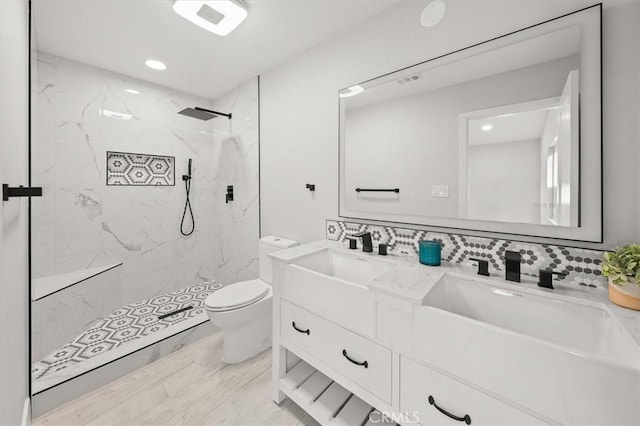 bathroom with toilet, vanity, and a tile shower