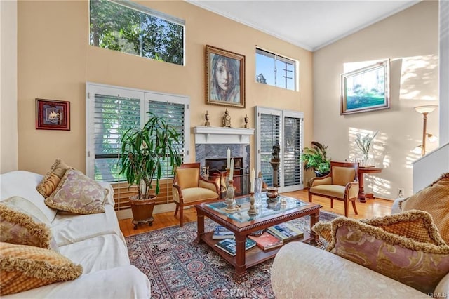 living area with a high ceiling, a high end fireplace, crown molding, and hardwood / wood-style flooring