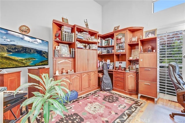 office featuring light hardwood / wood-style floors and a high ceiling